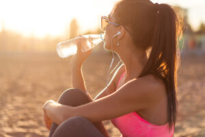 girl drinking water on the beach 